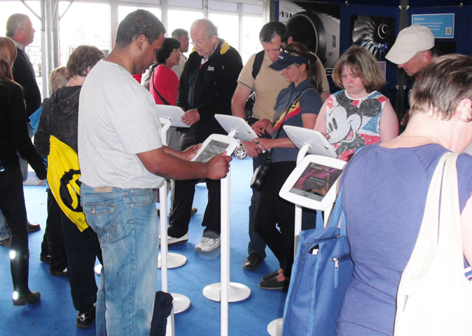 Several individuals engaging with touchscreen displays in a public space.