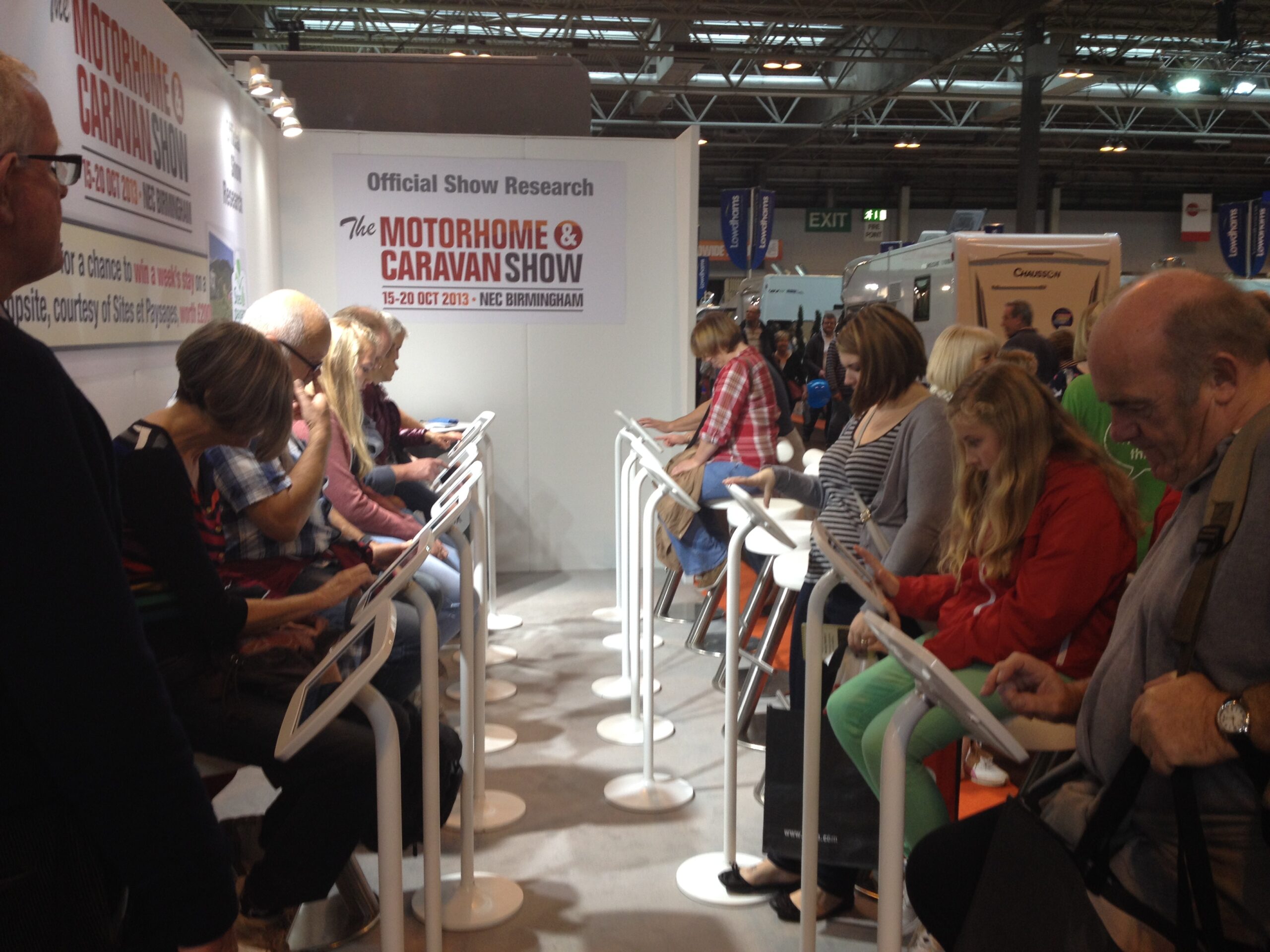 Group of people interacting with information kiosks at a trade show event.