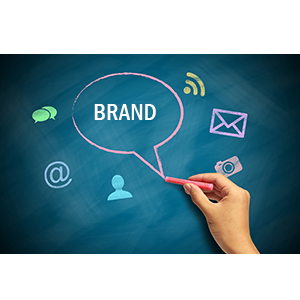 A hand writing the word 'BRAND' on a chalkboard surrounded by communication icons.