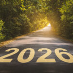 A road in a forest with the number 2026 painted on the pavement in large yellow letters.